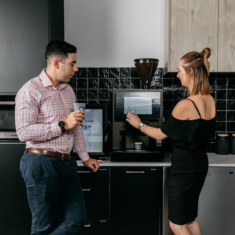 Two office employees drinking coffee from their workplace coffee machine
